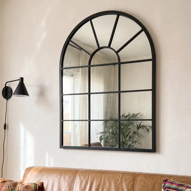 Miroir Verrière Arche cadre métal noir au-dessus d’un canapé en cuir