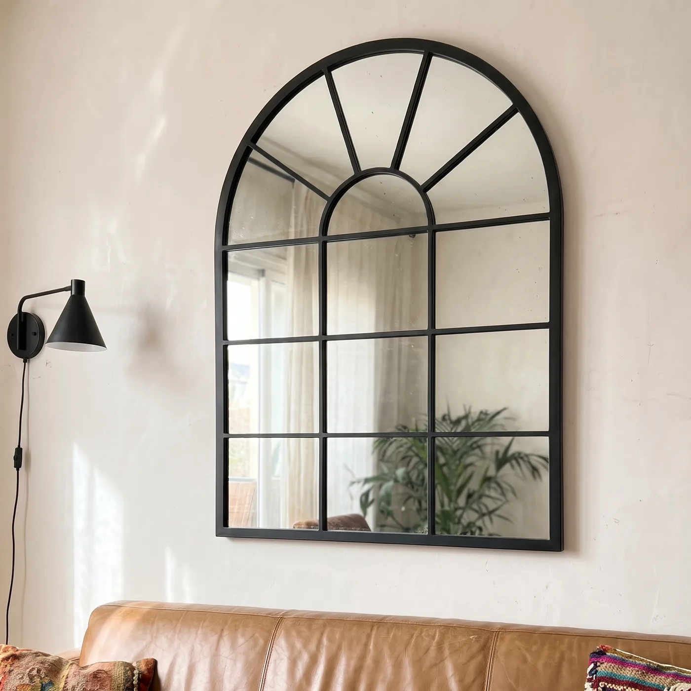 Miroir Verrière Arche cadre métal noir au-dessus d’un canapé en cuir